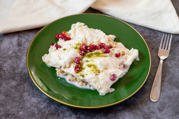 Gullac dessert on dark background. Traditional Ramadan dessert. Güllaç dessert decorated with pistachio and pomegranate. Turkish cuisine delicacies. Close up