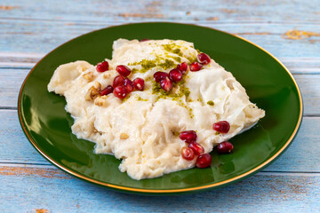 Gullac dessert on wooden background. Traditional Ramadan dessert. Güllaç dessert decorated with pistachio and pomegranate. Turkish cuisine delicacies. Close up
