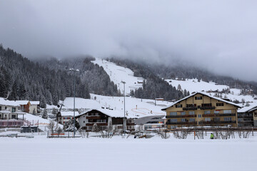 View to the foggy, snowy Landscape, Skiing Slope and the Houses of Churwalden, Switzerland in Wintertime