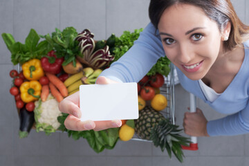 Woman pushing a trolley and holding a blank card