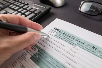 Fototapeta na wymiar a woman's hand filling out a tax form 1040