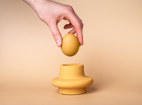 Woman hand putting beige egg in cup. Egg holder and server. Easter concept. High quality photo