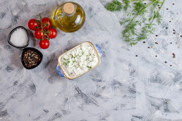 Tzatziki - yoghurt sauce with cucumber and dill on a grey background, traditional Greek cuisine. Flat lay, with copy space. Space for your product.