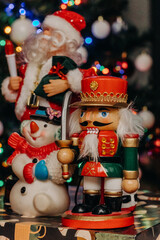 Nutcracker wooden toy on the background of festive Christmas lights. Nutcracker, snowman and santa claus figurines. Christmas. New Year