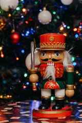 Nutcracker wooden toy on the background of festive Christmas lights. Nutcracker figurine. Bokeh. Christmas. New Year