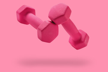 a pair of pink dumbbells levitate, on a pink background