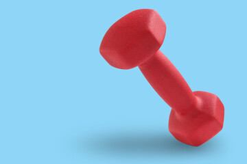 red dumbbell levitates on cyan background, casts a shadow