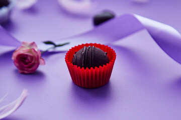 Chocolate festive candy. Trendy pink feathers, pink rose and purple ribbon. Very peri pantone color pattern.