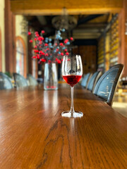 Selective focus closeup red wine glass on a wooden table in restaurant. Red wine with a flower background.
