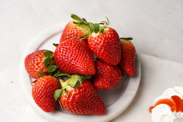 Mini-pavlova with fresh strawberries and red jam - delicious meringue cakes on marble board on off-white background
