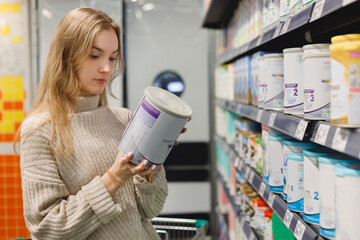 Woman buys infant milk formula at supermarket, portrait of young mother in shop mall