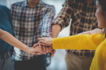 Group of Multiracial people putting their hands working together showing oneness symbol.