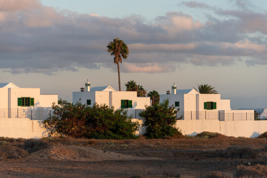 Casas blancas turísticas de Lanzarote en las Islas Canarias con palmeras y vegetación. Luz del atardecer en unas casas turísticas. turismo en España.
