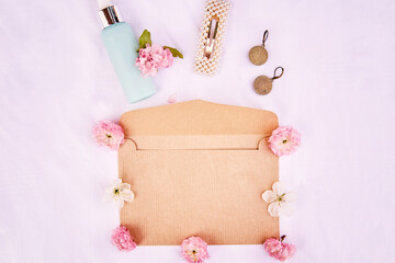 Elegant feminine spring envelope mockup with pink flowers, accessories, cosmetic gift on fabric white background. March 8 concept