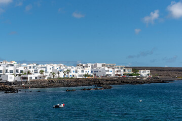 casas blancas en Punta Mujeres en Lanzarote en las Islas Canarias. Costa canaria con barcos, mar turquesas y casas al fondo. Paisaje y naturaleza de Espa&ntilde;a. 