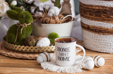 Easter morning. White-green colors. Iron vases with Easter eggs, flowers, a rabbit, a teapot and a cup in the interior of the living room. The concept of home comfort in the bright holiday of Easter.