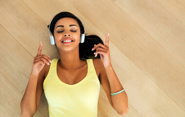 Love this song. High angle shot of a young woman listening to music while lying on a wooden floor.