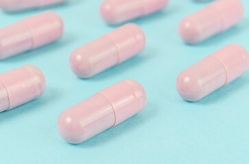 Pink capsule pills on blue background.