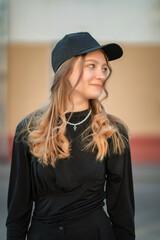 Portrait of a young beautiful girl in dark clothes on a city street.