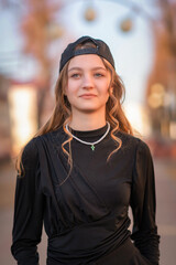 Portrait of a young beautiful girl in dark clothes on a city street.