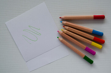 Small colored pencils and sheets of white paper on the table, top view. A template, a place for drawing,writing,sketches.