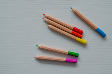 Colorful children's mini pencils on a white wooden background. School and kindergarten art supplies.