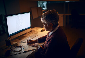 Fototapeta na wymiar Success requires constant dedication. Shot of a mature businesswoman working late in an office.