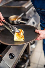 chef hand cooking Thin pancakes crepe rolls with ground meat in pan at a restaurant kitchen