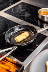 chef hand cooking Thin pancakes crepe rolls with ground meat in pan at a restaurant kitchen