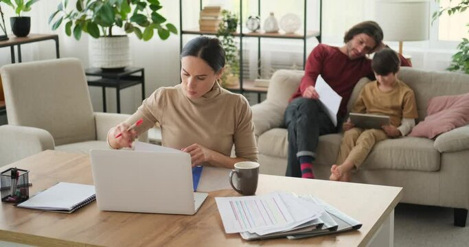 Mother analyzing documents and father helping son in doing homework on digital tablet at home