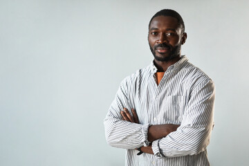 Minimal waist up portrait of successful African American businessman standing with arms crossed...