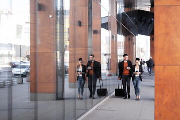 Business man and woman walking and drinking coffee. Businesspeople traveling together with luggage.