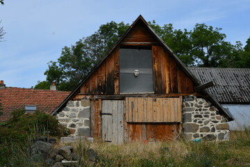 Fototapeta na wymiar Vieille maison ancienne restaurée avec son toit très pentu dans un petite village Auvergnat avec un masque de posé en façade
