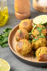 Chickpea falafel with lime and sauce on a plate and grey background vertical photo