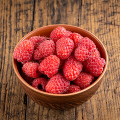 bowl of fresh fragrant raspberries on rustic wooden background. raspberries dessert close up