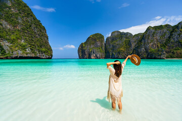 Young woman traveler relaxing and enjoying at beautiful tropical white sand beach at Maya bay in...