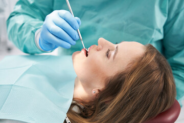 Doctor examining woman teeth with dental mirror