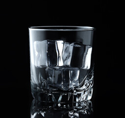 Ice cubes in empty glass on black background. Glass of water or whiskey and wine. Empty glass for alcoholic beverages