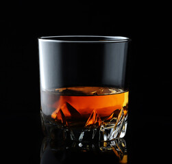 Scotch whiskey in an elegant glass on a black background with reflections.