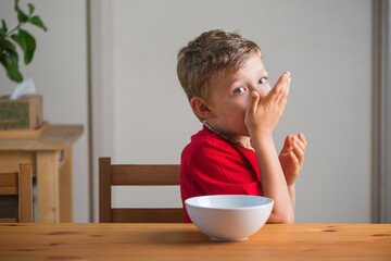 Cute boy eats granola for breakfast. Lifestyle portrait.