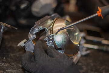 A mechanic in black gloves installs an LED lens into the headlight housing.Car headlight during repair and cleaning.The mechanic restores the headlight of the car.Restoration of automotive optics.