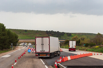 Refrigerated trucks changing lanes on a highway closed for works.