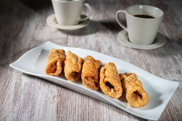 Plate with pestiños next to some cups of coffee, typical sweet of Holy Week.