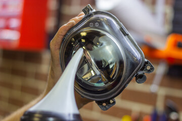 Car headlight during repair and cleaning. Perfectly smooth headlight glass. The mechanic restores the headlight of the car with the help of a chemical kettle. Restoration of automotive optics. © Dmitry Presnyakov