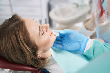 Obraz na płótnie Canvas Doctor comparing color of woman teeth with dental implant