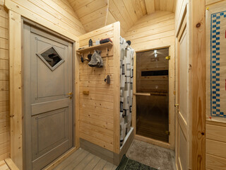 Wooden interior of modern bathhouse. Shower and door to sauna.