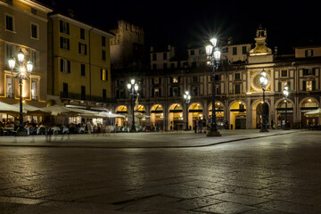 Fototapeta na wymiar Old pedestrian square at the italian Brescia city with the Clock tower on the background by night