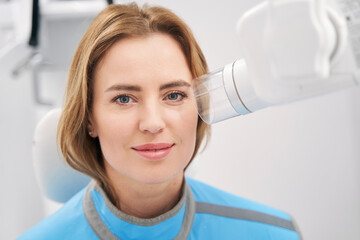 Woman sitting near diagnostic equipment in dental clinic