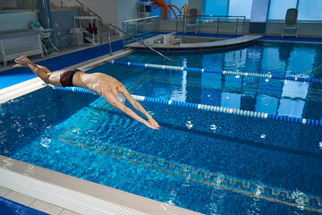 Active training of sporty man in the pool, night workout