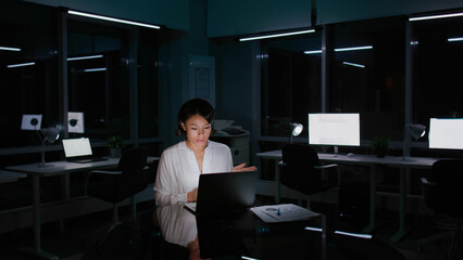 African-American businesswoman having video conference on laptop working late in dark empty office